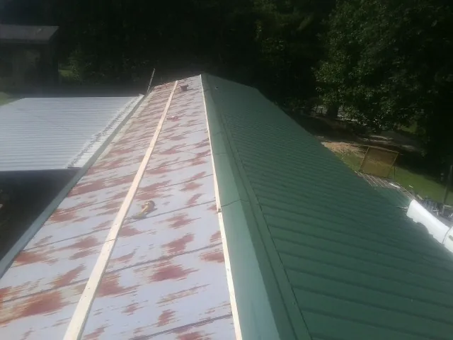 Old rusted panels beside newly installed green metal roofing — Wind Damage Roof Repair by Roofing Brothers in Tunkhannock