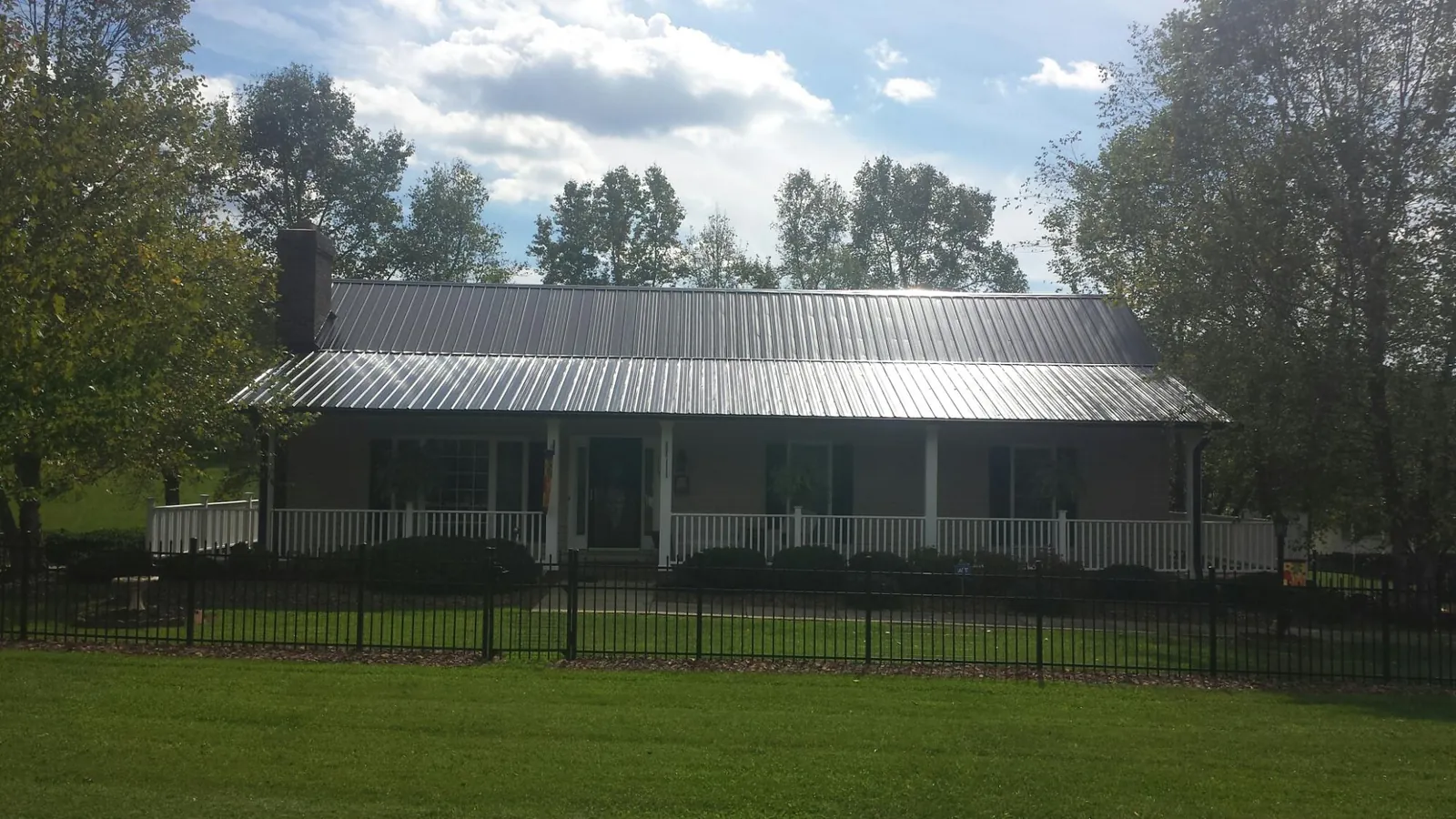 Gray metal roof on a brick ranch with a full width front porch — Gutter Guard Installation work by our crew in Tunkhannock