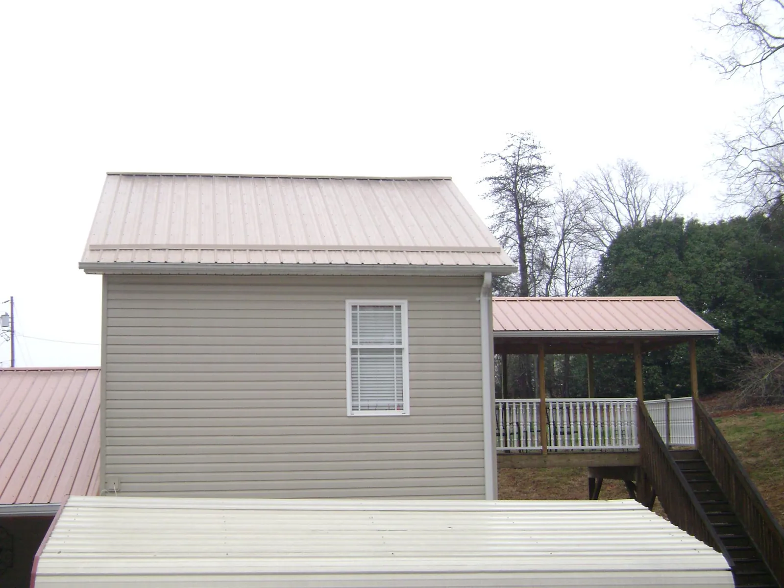 Tan metal roofs on a two story addition and attached porch, from a Roof Replacement job in Tunkhannock