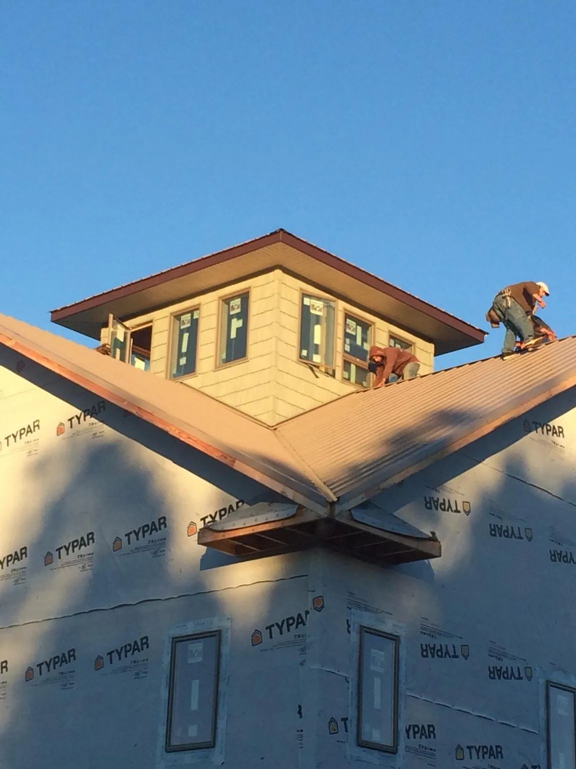 Roofers working around a rooftop cupola on a new metal roof at sunset — Roof Waterproofing in Tunkhannock by Roofing Brothers